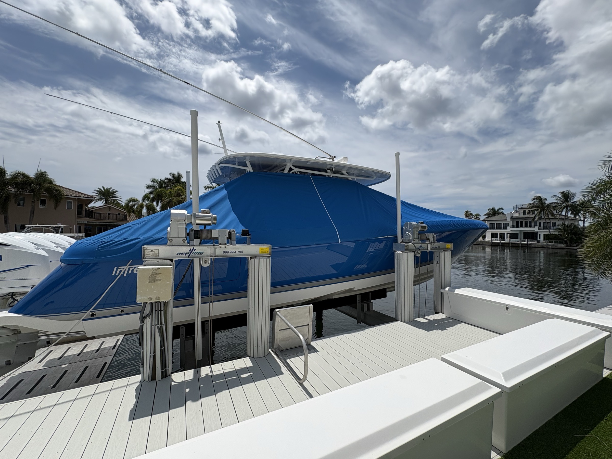 Custom royal blue full boat cover on an Intrepid center console on a boat lift in South Florida, tensioned under the T-top and around the rub rail with snaps
